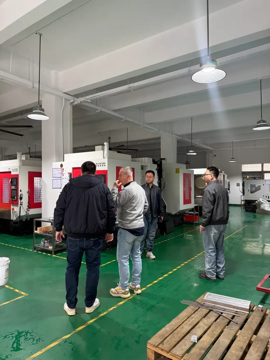 Customer and HERUIYUN engineers reviewing CNC production equipment on the factory floor