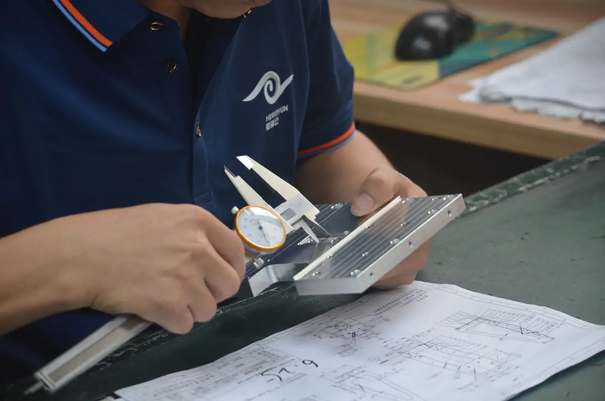 Technician checking a machined component with a dial caliper