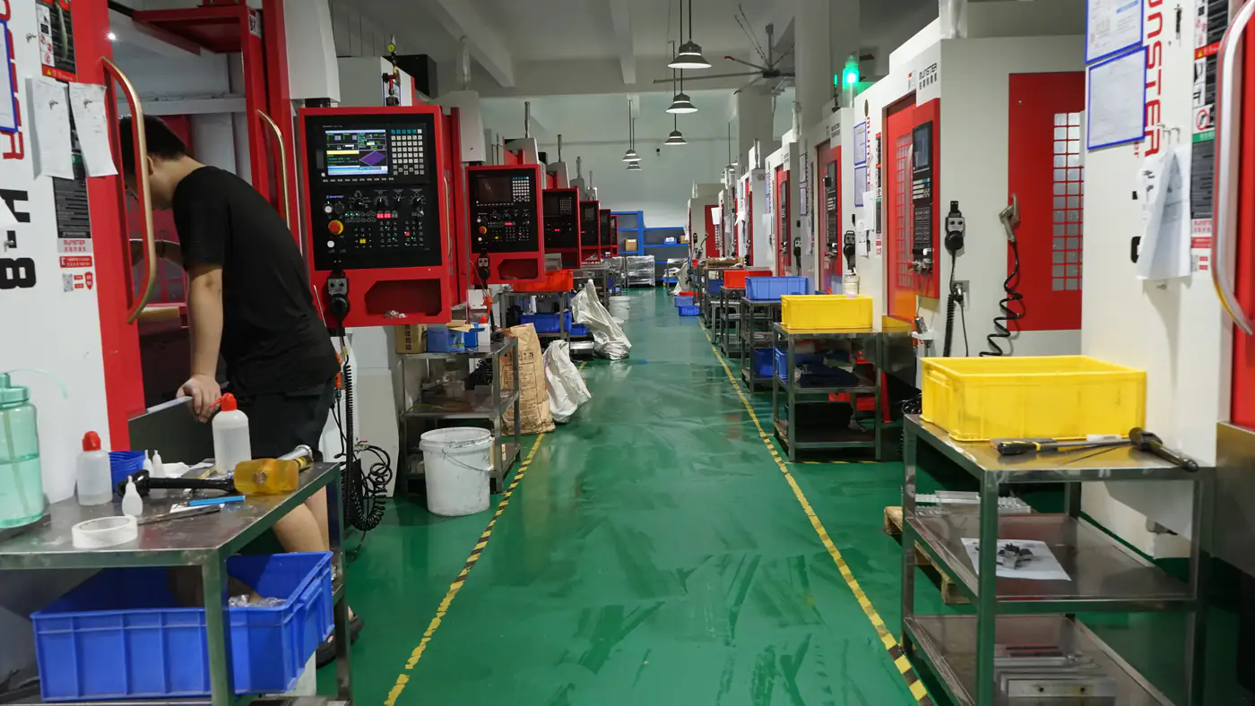Operator working beside CNC machining centers on the HERUIYUN factory floor