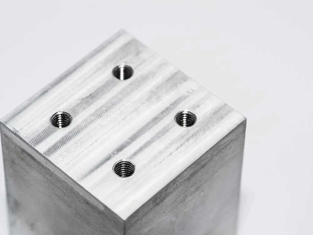 CNC-machined metal surface with visible tool marks and threaded holes