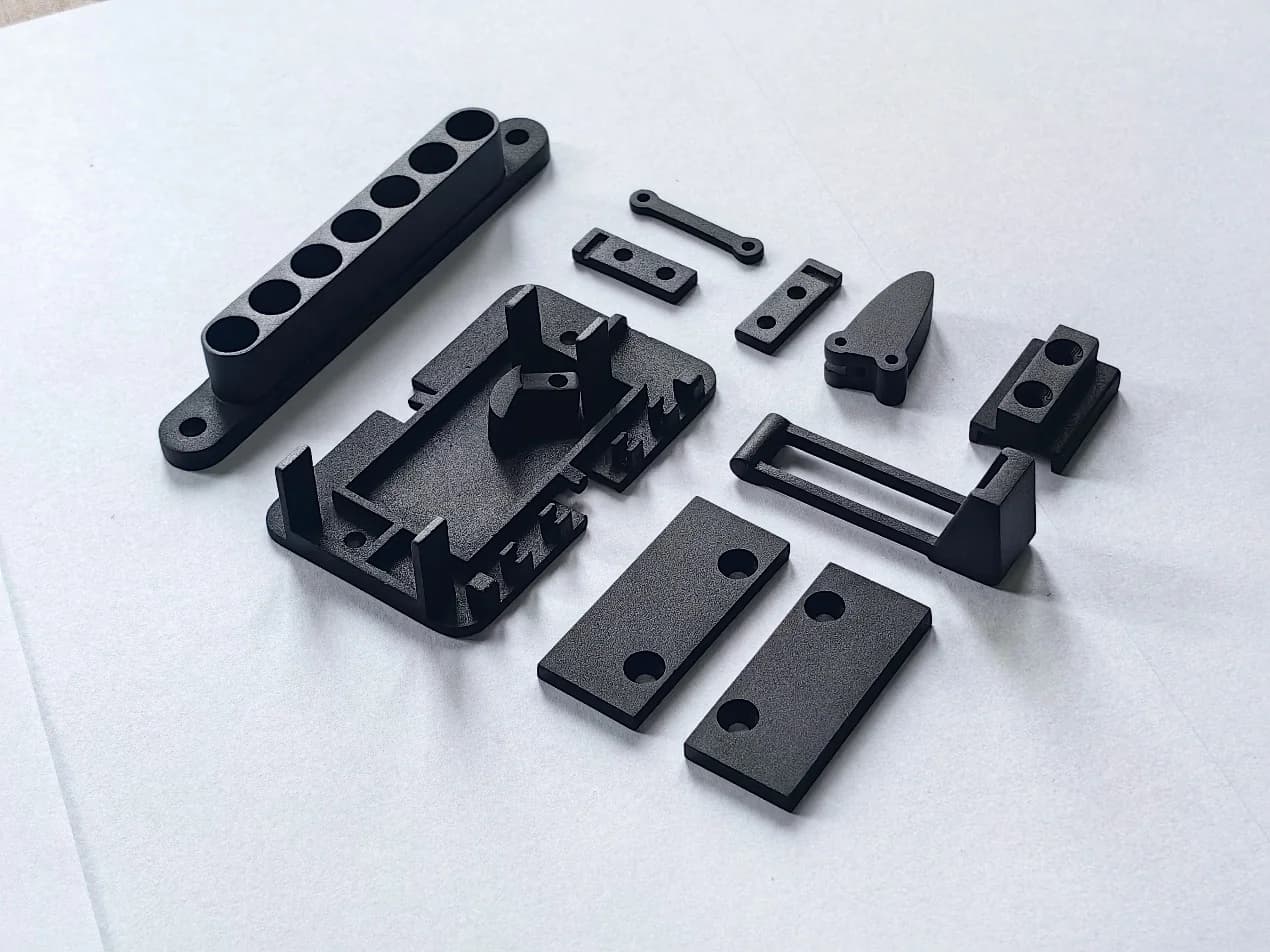 Dark prototype housings, plates and brackets arranged on a work surface