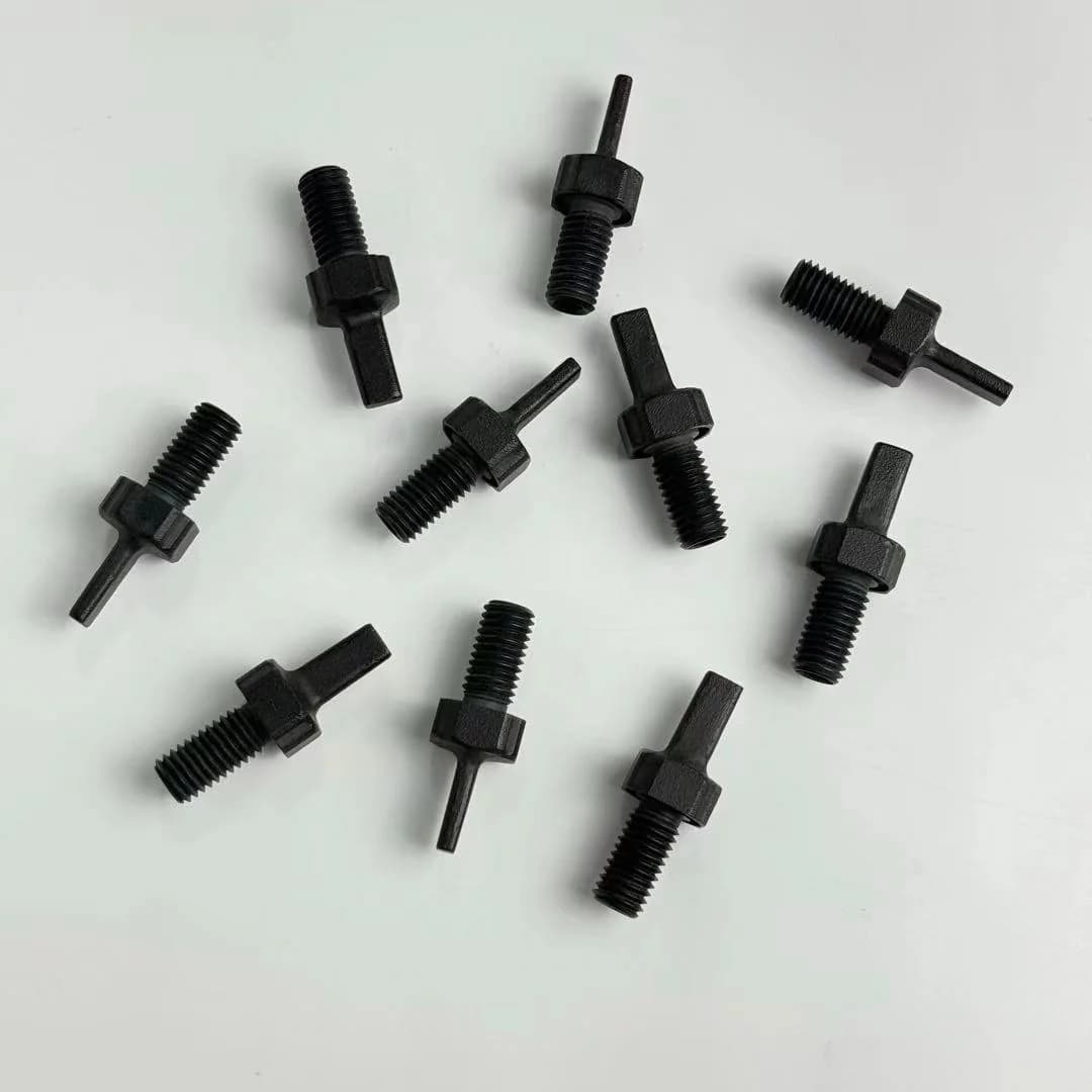 Small dark threaded components with projecting shafts on a pale surface